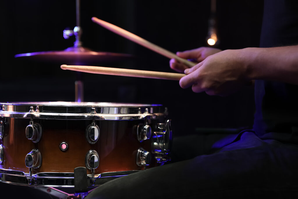 Drummer playing snare drum with sticks close up.